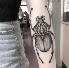 a black and white beetle tattoo on the arm