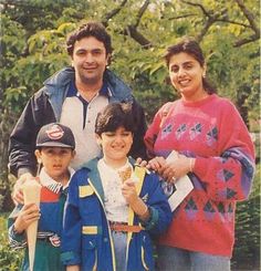 a man and two boys standing next to each other in front of some trees with food