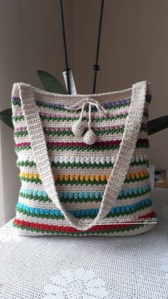 a multicolored crocheted bag sitting on top of a white doily