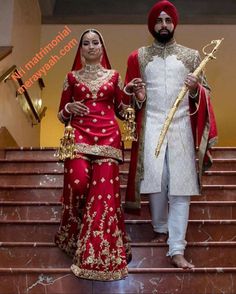 two people dressed in red and gold standing on stairs