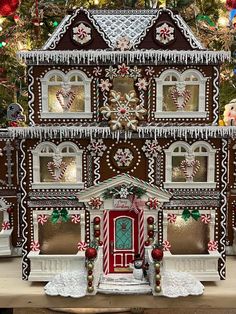 a large gingerbread house on display in front of a christmas tree