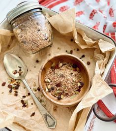 a wooden bowl filled with granola next to a spoon on top of a table