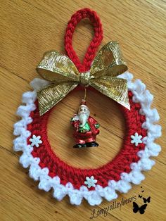 a crocheted christmas ornament hanging on a wooden floor with a gold bow