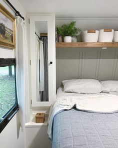 a bed in a small room with shelves on the wall next to it and a window