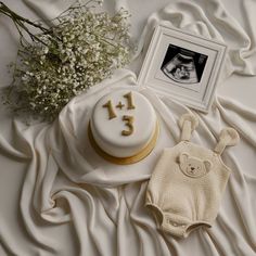 a baby's first birthday cake with a teddy bear on the table next to it