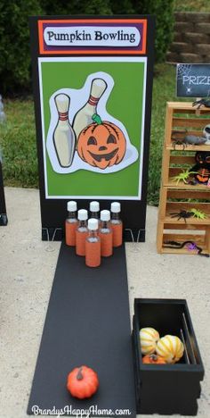 a pumpkin bowling game is set up on the sidewalk with bottles and an orange ball