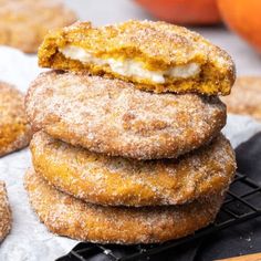 a stack of doughnuts sitting on top of a cooling rack next to oranges