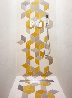 a bathroom with yellow and white tiles on the wall, shower head and hand held faucet