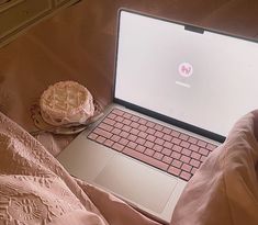 an open laptop computer sitting on top of a bed next to a cupcake covered in frosting