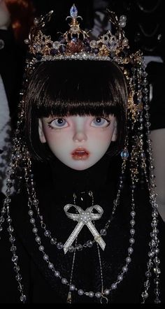 a close up of a doll wearing a tiara with pearls on it's head