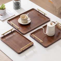 three wooden trays with coffee cups and teacups on them sitting on a table