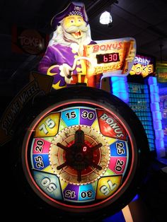 a brightly lit clock with an image of a wizard on it's face in front of neon signs