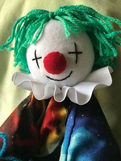 a close up of a stuffed toy with green hair and a clown face on it