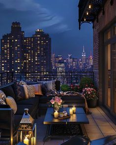 an outdoor living area with couches, tables and candles on the balcony at night