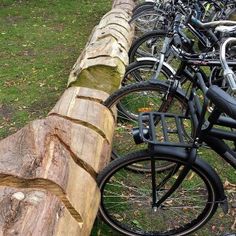 several bicycles are parked on the side of a wooden fence in front of a grassy area