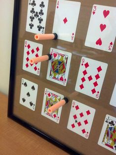 a framed playing card game with fours and fives on the cards, in front of a white wall