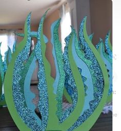 some blue and green paper art work in the shape of an ocean wave on a table