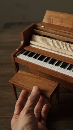 a hand is playing an organ on a wooden table