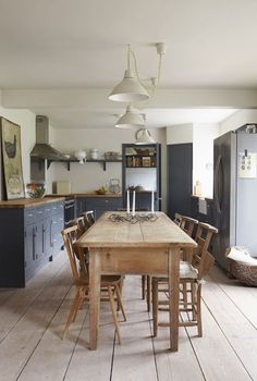 a wooden table sitting in the middle of a kitchen with lots of chairs around it