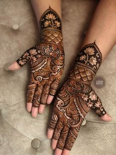 two hands with henna designs on them, one is showing it's intricate design