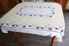 a table with a white cloth on it and black flowers around the edges, sitting in a room