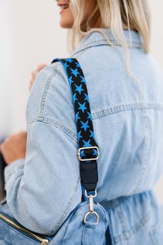 a woman wearing a blue jean jacket and carrying a black star print shoulder bag with gold hardwares