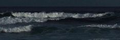 two surfers are riding the waves in the ocean at night, one is on his surfboard