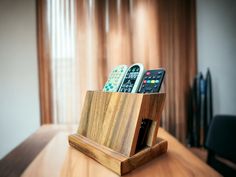 three remote controls in a wooden holder on a table