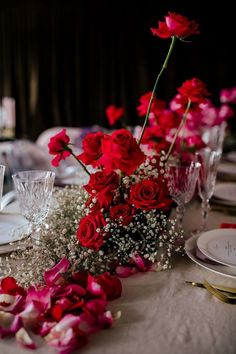 a table set with red roses and silverware for a formal dinner or wedding reception