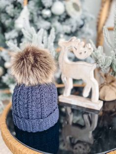 a knitted hat sitting on top of a wooden table next to a christmas tree