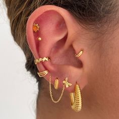 a woman wearing gold ear cuffs with pineapples on them