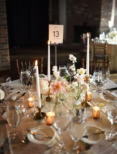 the table is set with candles, plates and place settings for guests to sit at