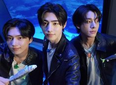 three young men standing next to each other in front of a blue screen with an aquarium behind them