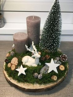 two candles are sitting on a wood slice with moss and stars around it, surrounded by other christmas decorations