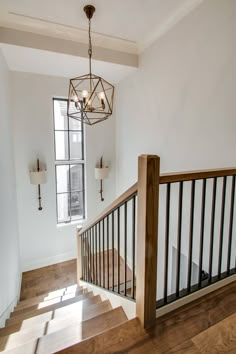 an empty staircase with wooden handrails and chandelier