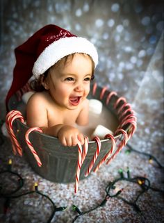 a baby in a bucket with candy canes and a santa's hat on