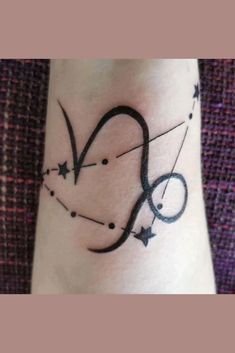 a wrist tattoo with the letter q on it's left side, and stars in the middle