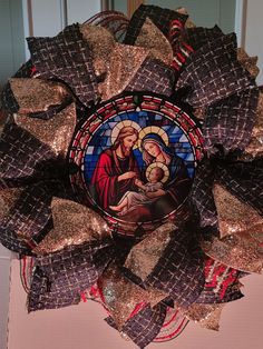 a wreath decorated with stained glass and gold sequins depicting the birth of jesus