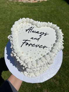 someone holding up a heart shaped cake with the words always and forever written on it