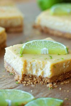 a slice of key lime cheesecake on top of a cutting board with limes around it