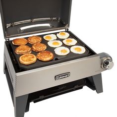 an electric grill with eggs and pancakes cooking on it