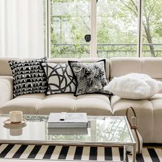 a living room with a couch, coffee table and large window overlooking the trees outside