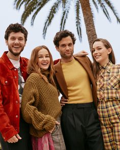 a group of people standing next to each other in front of a palm tree on the beach