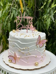 a white cake with pink frosting and butterflies on top, sitting on a table