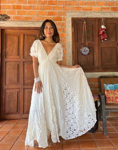 a woman standing in front of a wooden door wearing a white dress