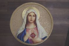 an image of the virgin mary holding a heart in her hands on a wooden surface