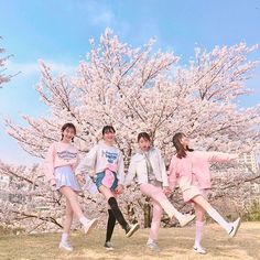 four young people are posing for a photo in front of cherry blossom trees with their legs spread out