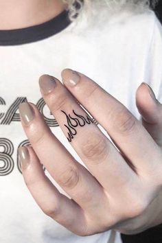 a woman's hand with a small tattoo on her left thumb and the word love written in black ink