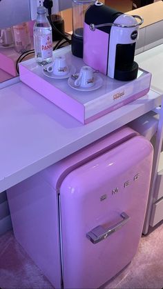 a purple refrigerator sitting on top of a counter next to a coffee pot and cup