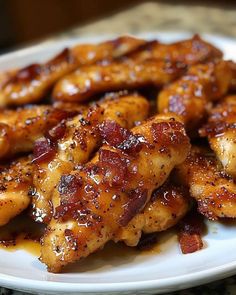 chicken wings covered in bbq sauce on a white plate with sesame seeds and seasoning